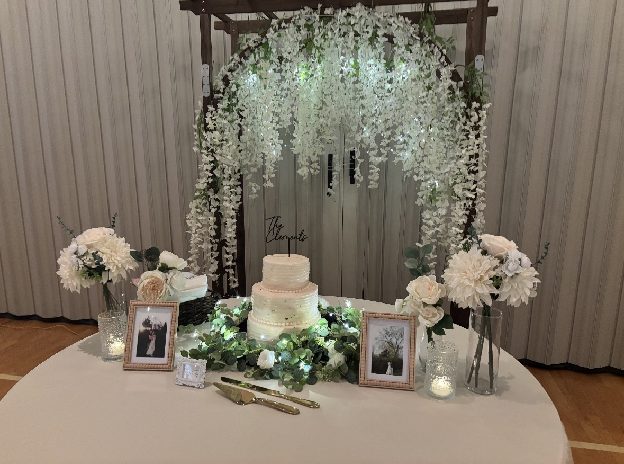 Home 4 A wedding cake table dressed with white florals, greenery and framed family photographs