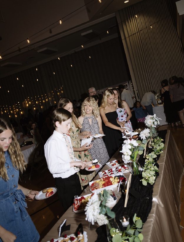 Home 3 Family and friends of all ages gathered along a buffet table, talking as they serve